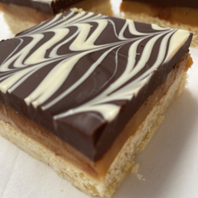 A millionaires shortbread close up with a marbled top layer, a caramel middle section and a biscuit base