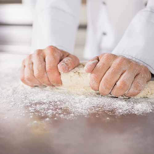 Close up of baker preparing dough in the kitchen of the bakery