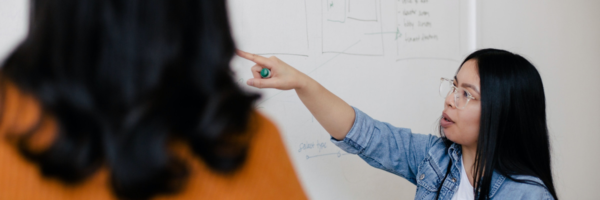A woman points to a technical drawing on a whiteboard